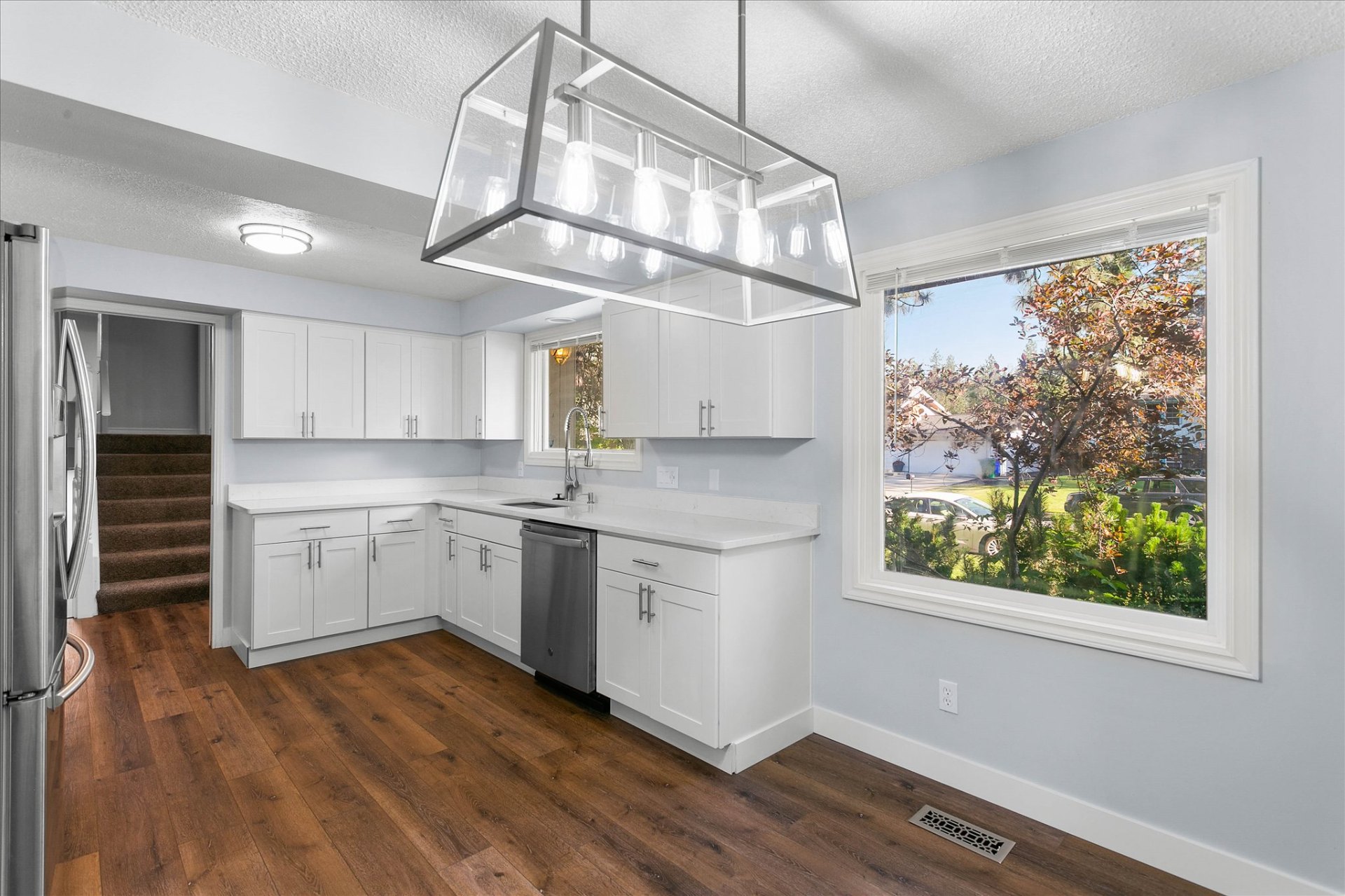 Renovated kitchen with white shaker cabinets and hardwood floors